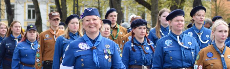 Joukko partiolaisasuihin pukeutuneita ihmisiä.